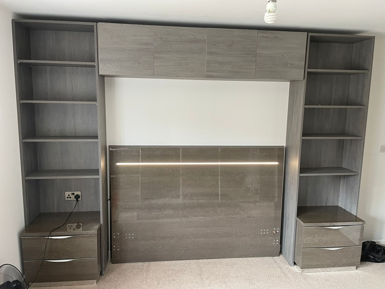 Custom grey overbed storage unit with cupboards, shelving and bedside drawers